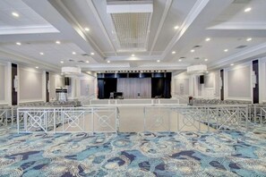 A large, well-lit conference room with a stage, seating, and a patterned carpet. - Furnished cozy 2-bedroom/2-bathroom condo 
in the resort-style gated community. (Boynton Beach)