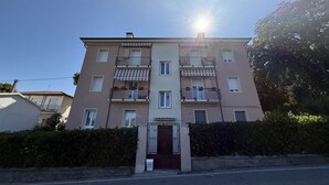 Un edificio residencial de varios pisos con entrada central, balcones y cielo despejado.