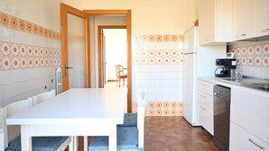 Una cocina con mesa, sillas, refrigerador y lavavajillas.