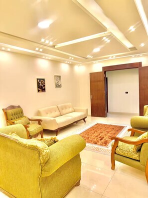A modern living room with a sofa, armchairs, and a patterned rug. - Luxury 2 Bedroom Apartment (Amman)