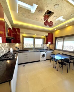 Une cuisine moderne dotée d’un îlot central, d’un lave-linge encastré et d’un coin repas avec une table et des chaises.