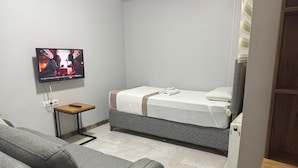 A hotel room with a bed, a television mounted on the wall, a small table, and a sofa.