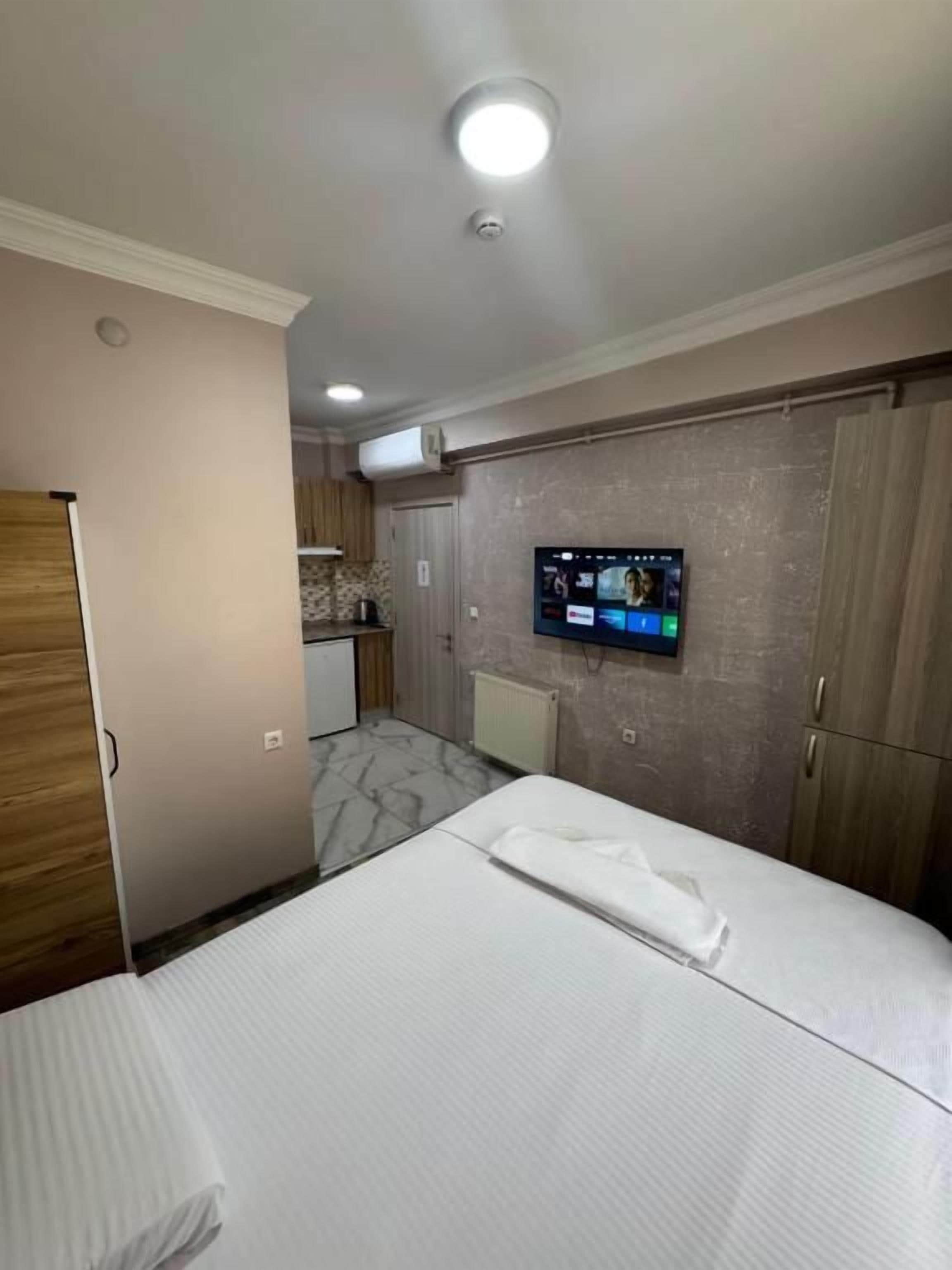 Una habitación de hotel con una cama, un televisor en la pared y un armario.