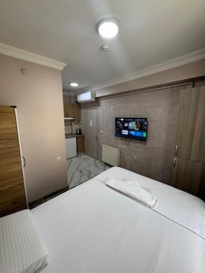 Una habitación de hotel con una cama, un televisor en la pared y un armario.
