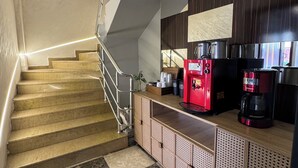 A staircase leading to a kitchen area with a coffee machine and a red appliance on the counter.