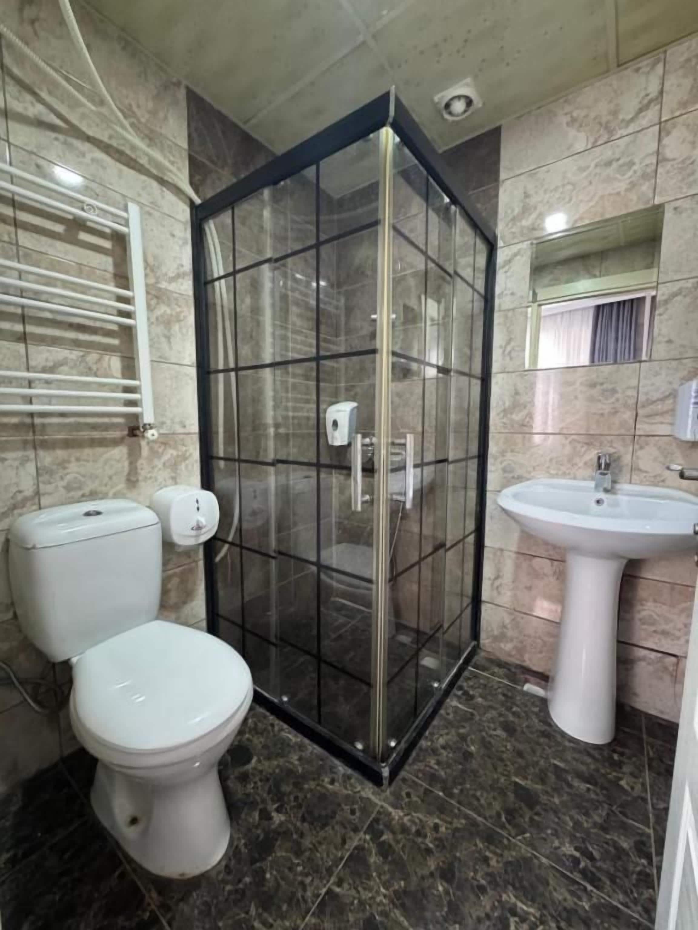 Casa de banho com cabine de duche em vidro, sanita e lavatório.