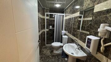 Une salle de bain comprenant des toilettes, un lavabo et un espace douche.