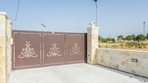 A gated entrance with decorative white patterns, a stone wall, and a clear sky in the background. - EmyHouse54 - Villetta con piscina (Martina Franca)