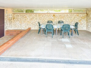 Eine Außenpatio mit einer Steinmauer, einem Tisch mit Stühlen und einer kleinen Stufe, die zu einer Tür führt.