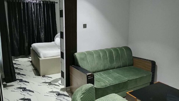 A room with a bed, a green sofa, a small table, and a mirror. - ERATON HOTEL (Warri)