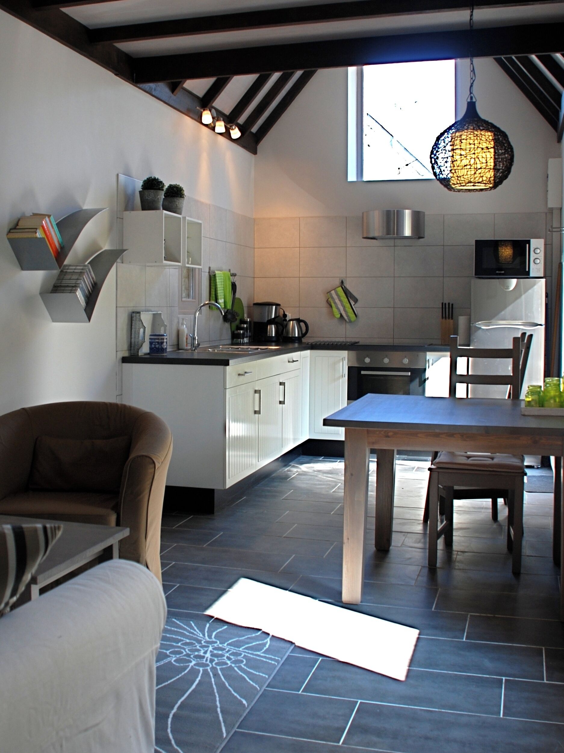 A modern kitchen with white cabinets, a dining table, and a hanging light fixture.