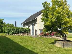A house with a stone facade, a sloped roof, and a well-maintained lawn. - La Cabane; a comfortable, detached gîte for two with a spacious terrace (Les Bois d'Anjou)