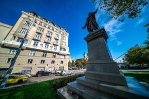 Eine Statue auf einem Sockel, im Hintergrund ein Gebäude.