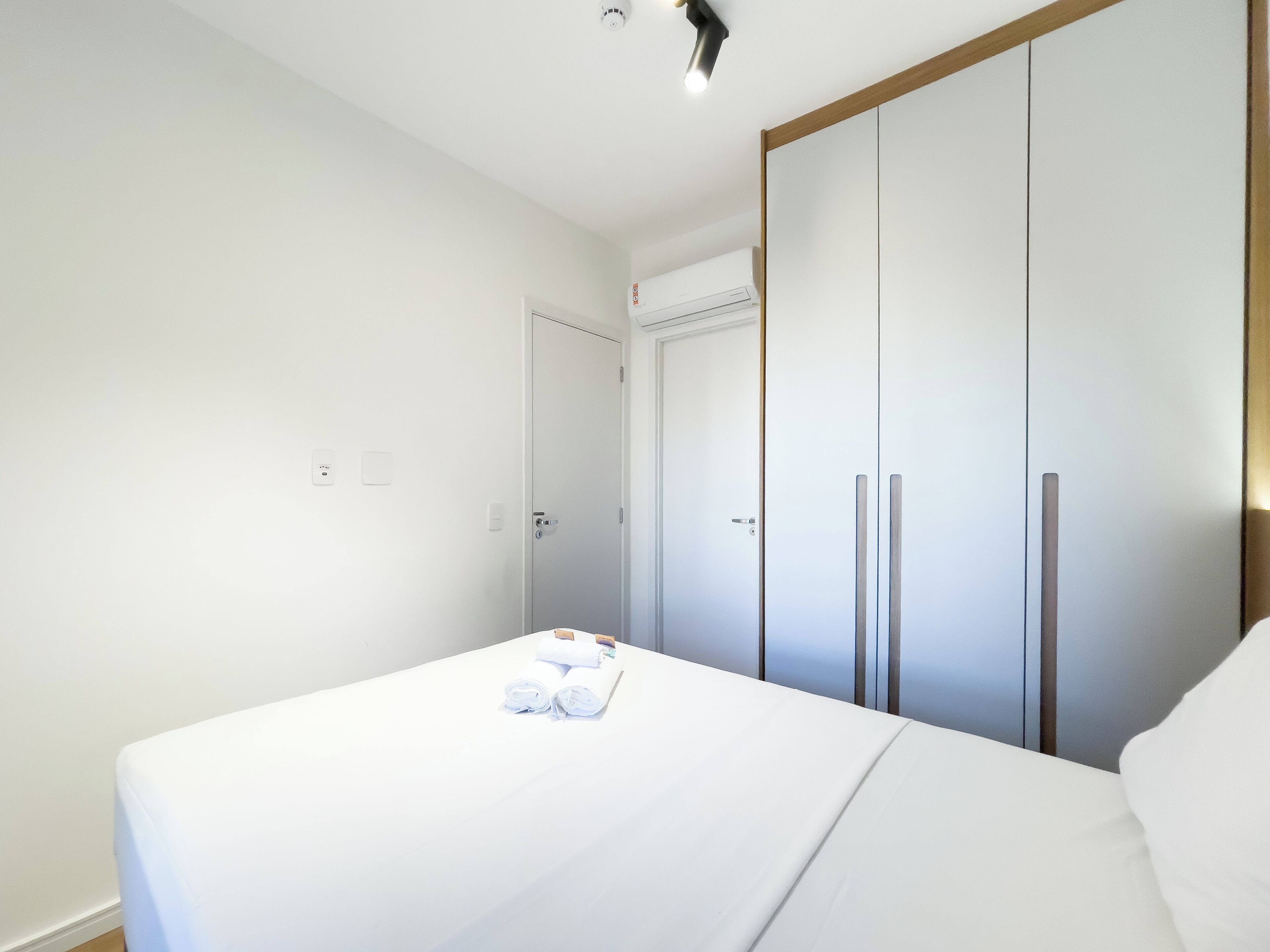 A hotel room with a bed, a wardrobe, and a door.