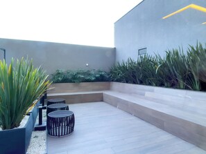 A modern outdoor seating area with a flat roof, surrounded by planters with various plants. - My One Estação Japão Liberdade (São Paulo)