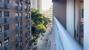 Un edificio de gran altura con varios balcones, una calle con una cinta roja y un cielo despejado.