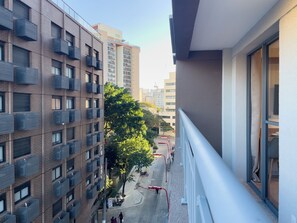 Un edifici alt amb múltiples balcons, un carrer amb una cinta vermella i un cel serè.