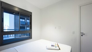 Habitación de hotel con cama, ventana con vista a la ciudad, puerta y un interruptor de luz.
