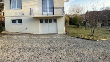 A two-story house with a garage, a satellite dish, and a gravel driveway.