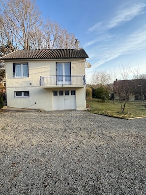 Een twee verdiepingen tellend huis met garage, schotelantenne en een oprit met grind.