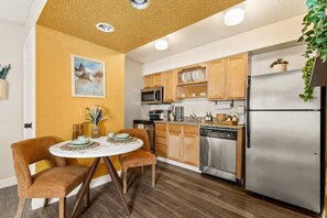 Eine moderne Küche mit Holzschränken, Edelstahlgeräten und einem Essbereich mit rundem Tisch und Stühlen.