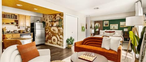 Un salón moderno con un sofá, una mesa de centro y una zona de cocina con un refrigerador y armarios.