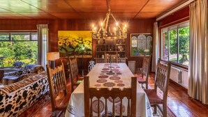 A dining area with a wooden ceiling, a chandelier, a table with patterned tablecloths, and a view of greenery outside. - Villa with Large Garden and Pool (La Cavada)