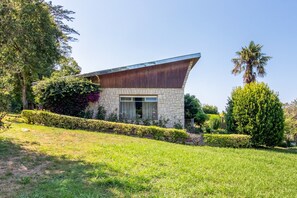 Ein modernes Haus mit Naturstein-Fassade, großen Fenstern und einem geneigten Dach.