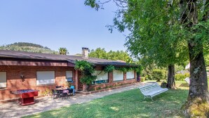 A brick building with a covered patio, outdoor seating, and a tree. - Villa with Large Garden and Pool (La Cavada)