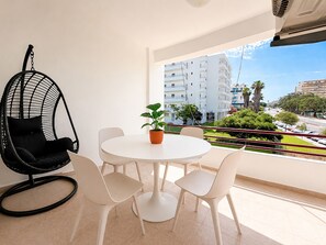 A balcony with a round table, white chairs, a hanging chair, and a potted plant. - Apartment Praia Rocha | Pool | Modern Vogue (Portimão)