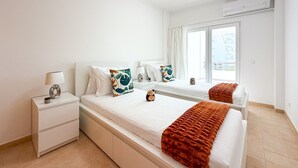 Ein Hotelzimmer mit einem Bett, Nachttischen, einer Lampe und einem Fenster mit Vorhängen.