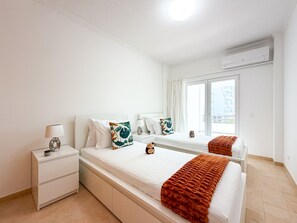 A hotel room with a bed, bedside tables, a lamp, and a window with curtains. - Apartment Praia Rocha | Pool | Modern Vogue (Portimão)