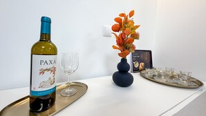 Eine Flasche PAXÁ Sauvignon Blanc auf einem Tablett mit einem Weinglas, eine dekorative Vase mit Herbstlaub und ein Tablett mit Gläsern und einer Speisekarte auf einem weißen Tisch.