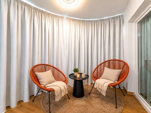 A room with two wicker chairs, a small round table with a candle, and a large window with curtains. - Apartment Praia Rocha | Pool | Modern Vogue (Portimão)