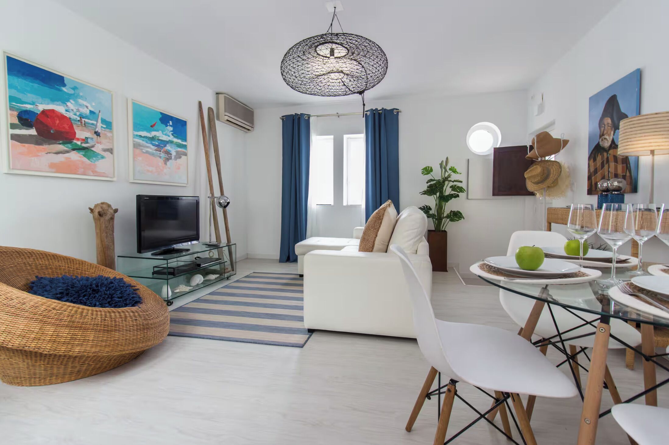 A modern living room with a sofa, TV, and dining area with chairs and a table.