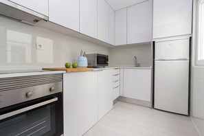 A modern kitchen with white cabinets, a stainless steel refrigerator, a microwave, and an oven. - Corema Apartment, Sesimbra, Setúbal (Sesimbra)