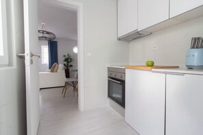 A modern kitchen with white cabinetry, a built-in oven, and a blue appliance on the countertop. - Corema Apartment, Sesimbra, Setúbal (Sesimbra)