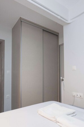 Ein Hotelzimmer mit Bett, Schrank und Steckdose an der Wand.