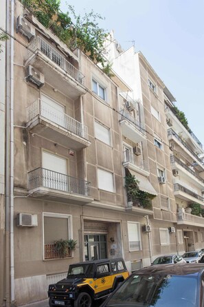 A multi-story residential building with balconies, air conditioning units, and a parked vehicle in front. - Refined 1 Bd Home in Athens Kolonaki (Athina)