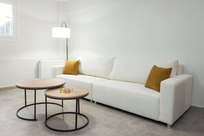 A modern living room with a white sofa, two round tables, and a floor lamp. - Refined 1 Bd Home in Athens Kolonaki (Athina)