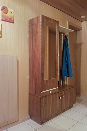 A wooden wardrobe with a mirror and a coat hanging on it. - Bergfreude Appartement/Fewo 4-Bettwohnung by Interhome (Saas-Grund)
