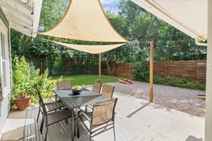 Eine Terrasse im Freien mit Tisch und Stühlen, umgeben von einem Holenzaun und Pflanzen.