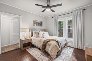Ein Schlafzimmer mit Bett, Nachttisch, Lampe und Deckenventilator.