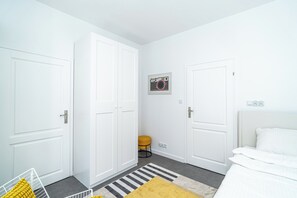 Habitación de hotel con paredes blancas, una cama, una mesita redonda y una alfombra a rayas.