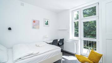 Un dormitorio moderno con cama, escritorio, silla y un amplio ventanal.
