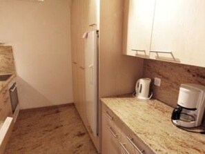 Eine kleine Küche mit Kühlschrank, Kaffeemaschine und Mikrowelle.