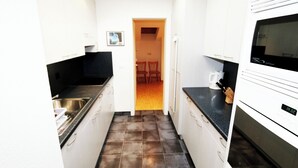 A narrow kitchen with white cabinets, a black countertop, and a tiled floor. - Cristal Appartement/Fewo 6-Bettwohnung Nr. 25 by Interhome (Saas-Fee)