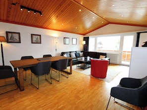 A modern interior with a wooden ceiling, a dining area with a table and chairs, a sofa, and a red ottoman. - Cristal Appartement/Fewo 6-Bettwohnung Nr. 25 by Interhome (Saas-Fee)