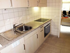 Eine moderne Küche mit doppelter Spüle, Armatur aus Edelstahl und eingebautem Backofen.