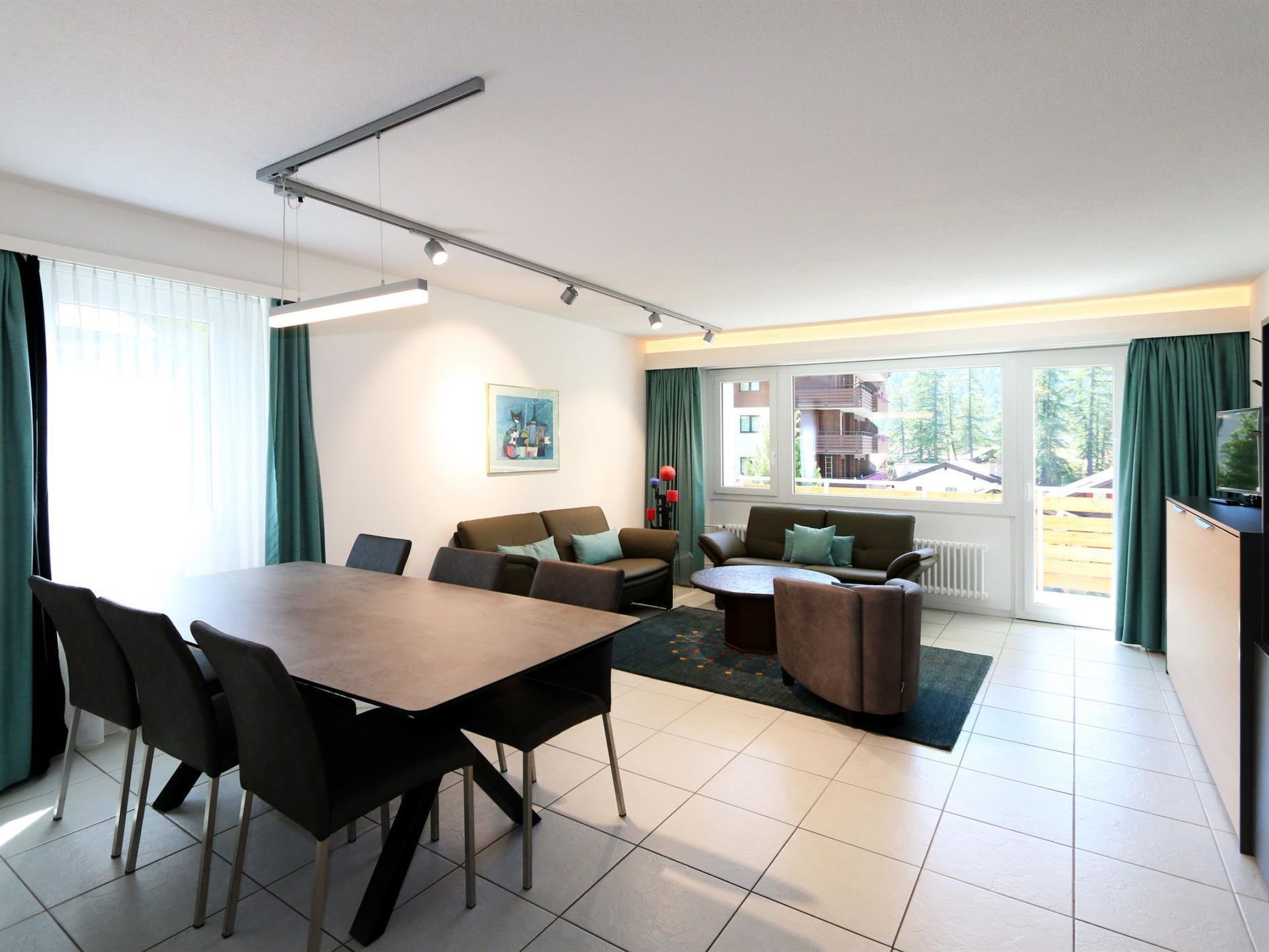 Ein modernes Wohnzimmer mit Essbereich, großen Fenstern und Blick auf ein Gebäude.